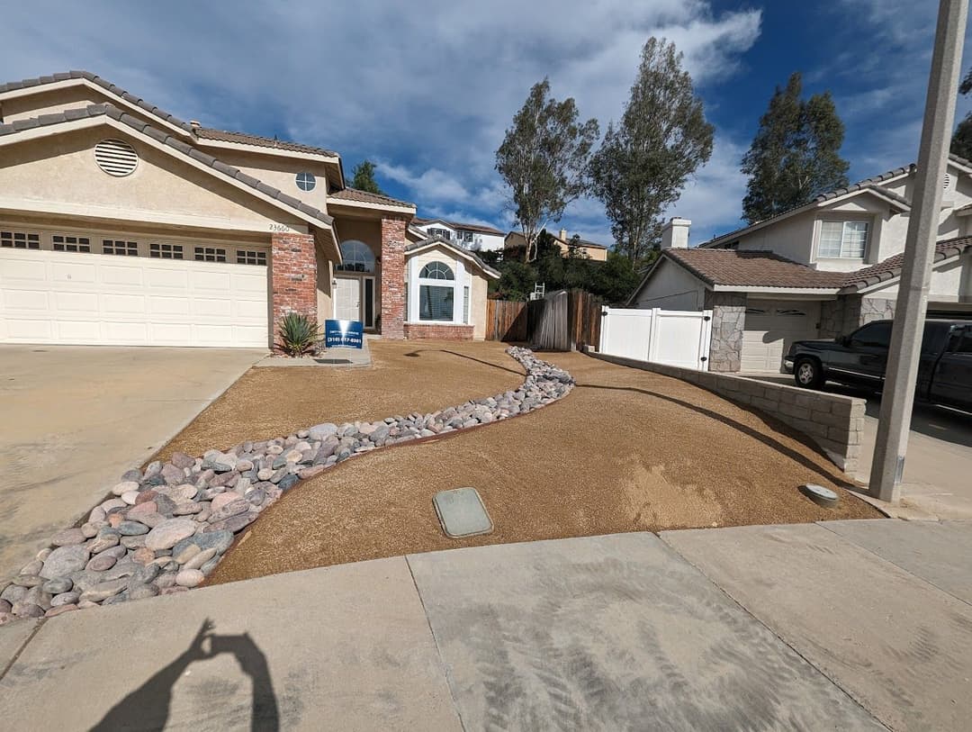 Newly landscaped front yard with gravel pathway, low-maintenance design, and clear blue sky.