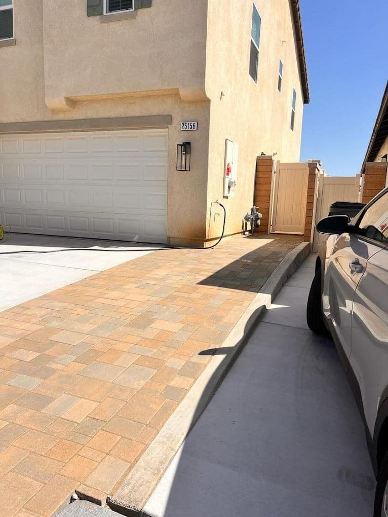 Residential driveway with paver stones, garage, and clear blue sky, modern home exterior.