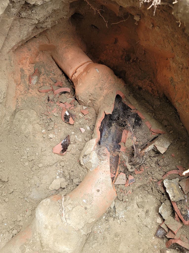 Broken clay sewer pipe with damage and soil exposure, revealing underground repair needs.