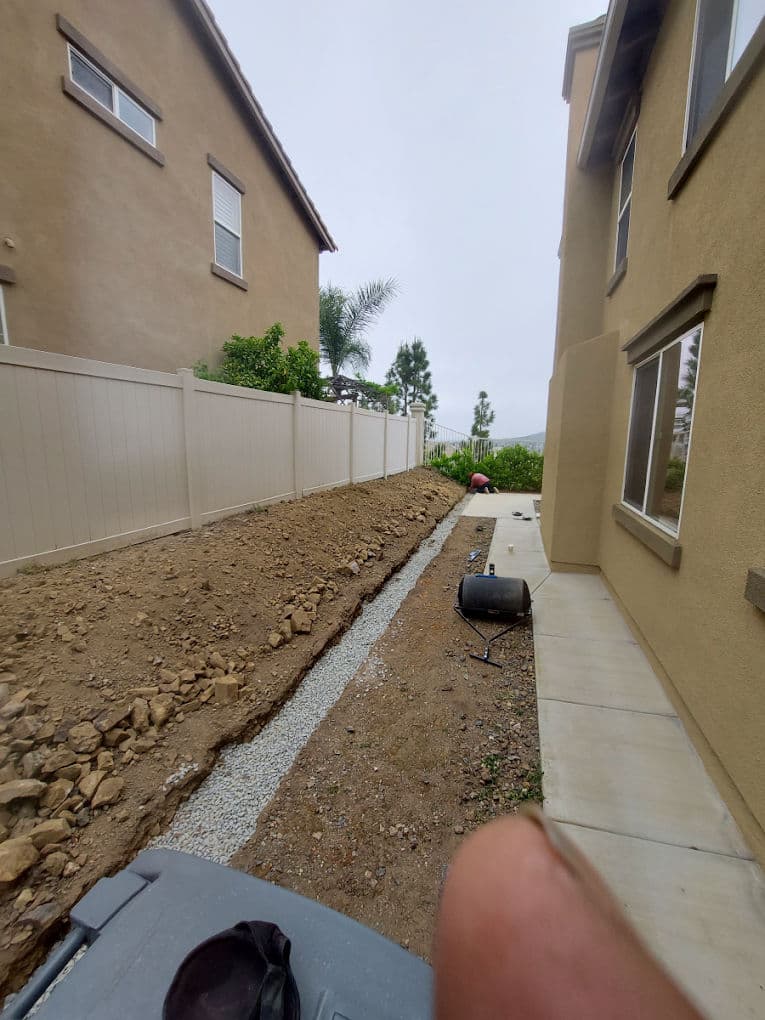 Side view of a home showing a gravel pathway and landscaped area next to a fence.