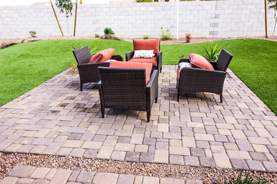 Cozy outdoor seating area with four wicker chairs and a small table on a stone patio.