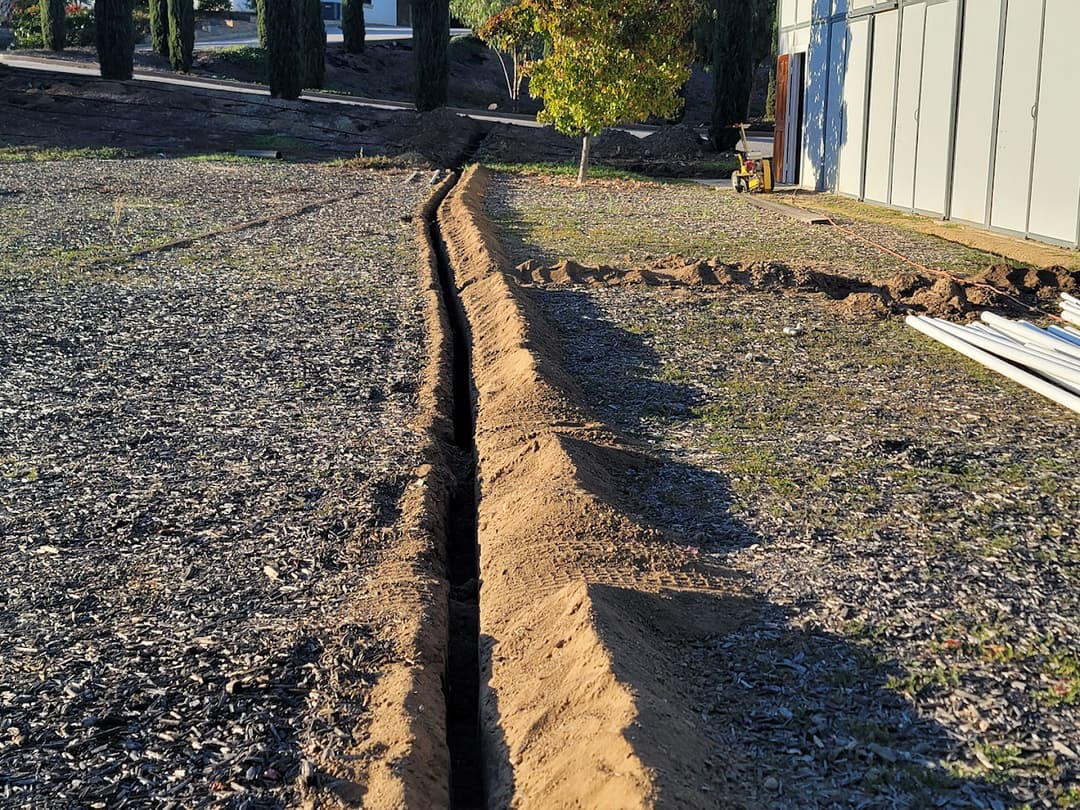 Trenched soil in a yard showing preparation for landscaping or irrigation installation.
