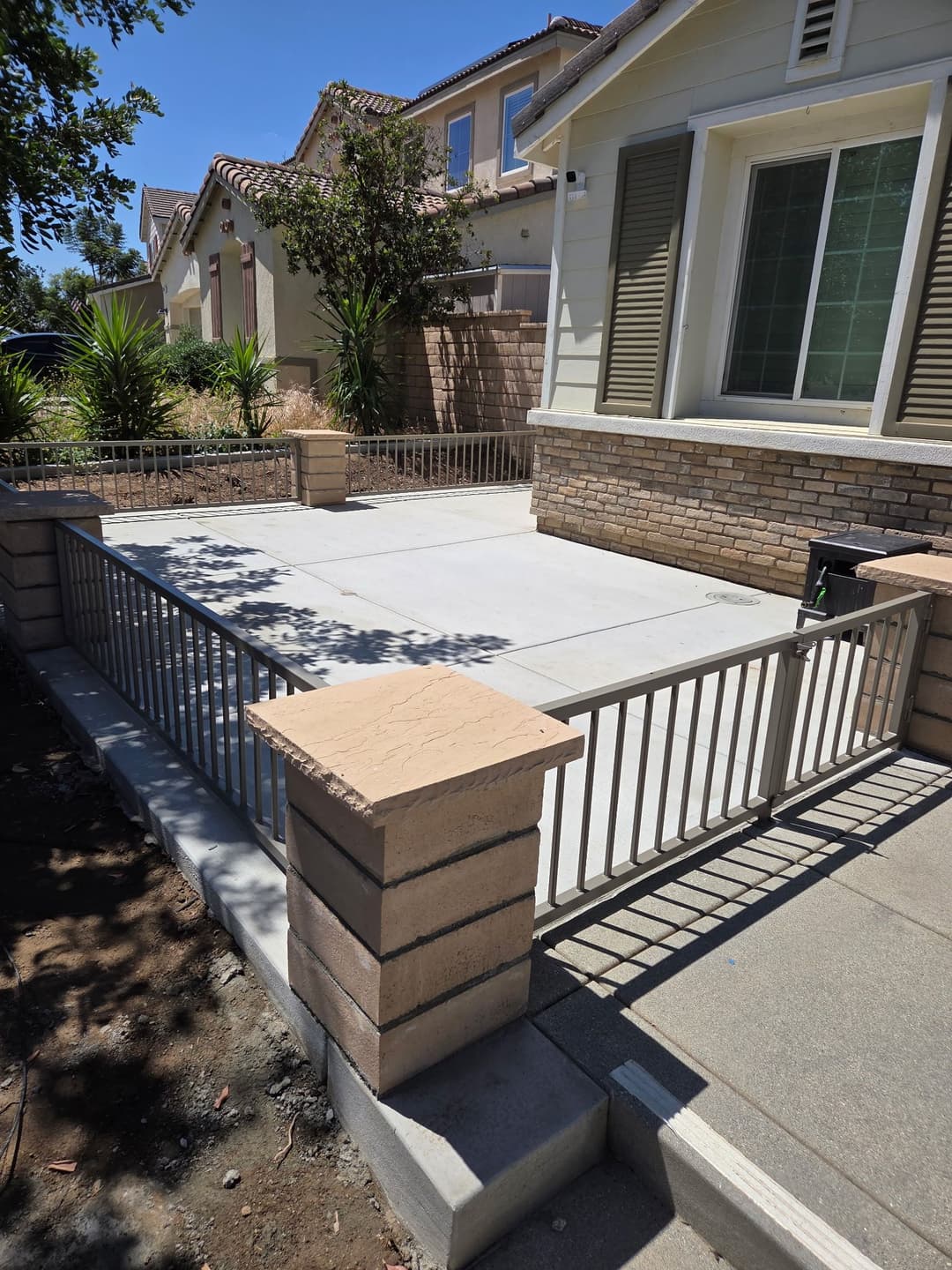 Modern patio with concrete flooring and decorative stone fencing in a residential area.