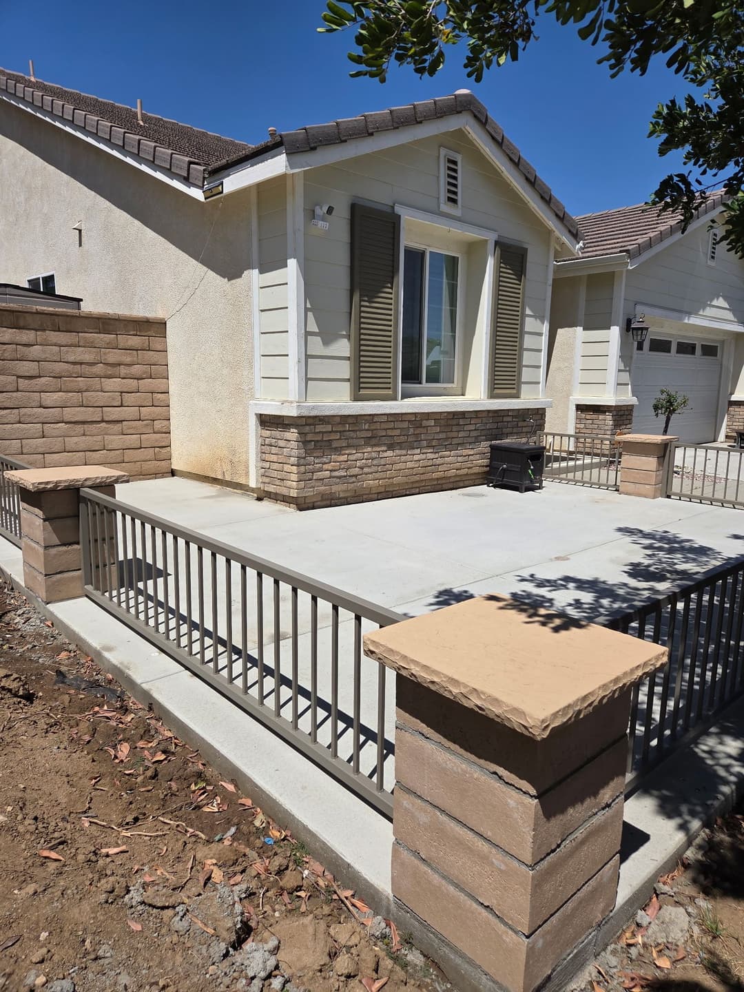 Modern home exterior with porch, stone accents, and decorative railing under clear blue sky.